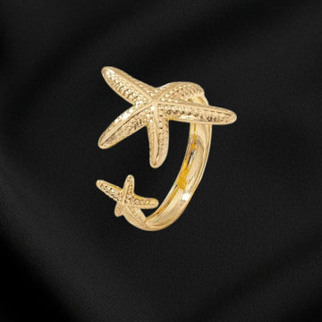 Gold starfish-shaped ring on a black fabric background