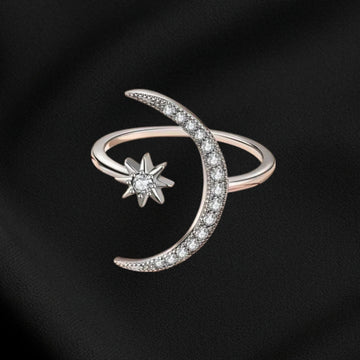 Silver ring with moon and star design on a black background