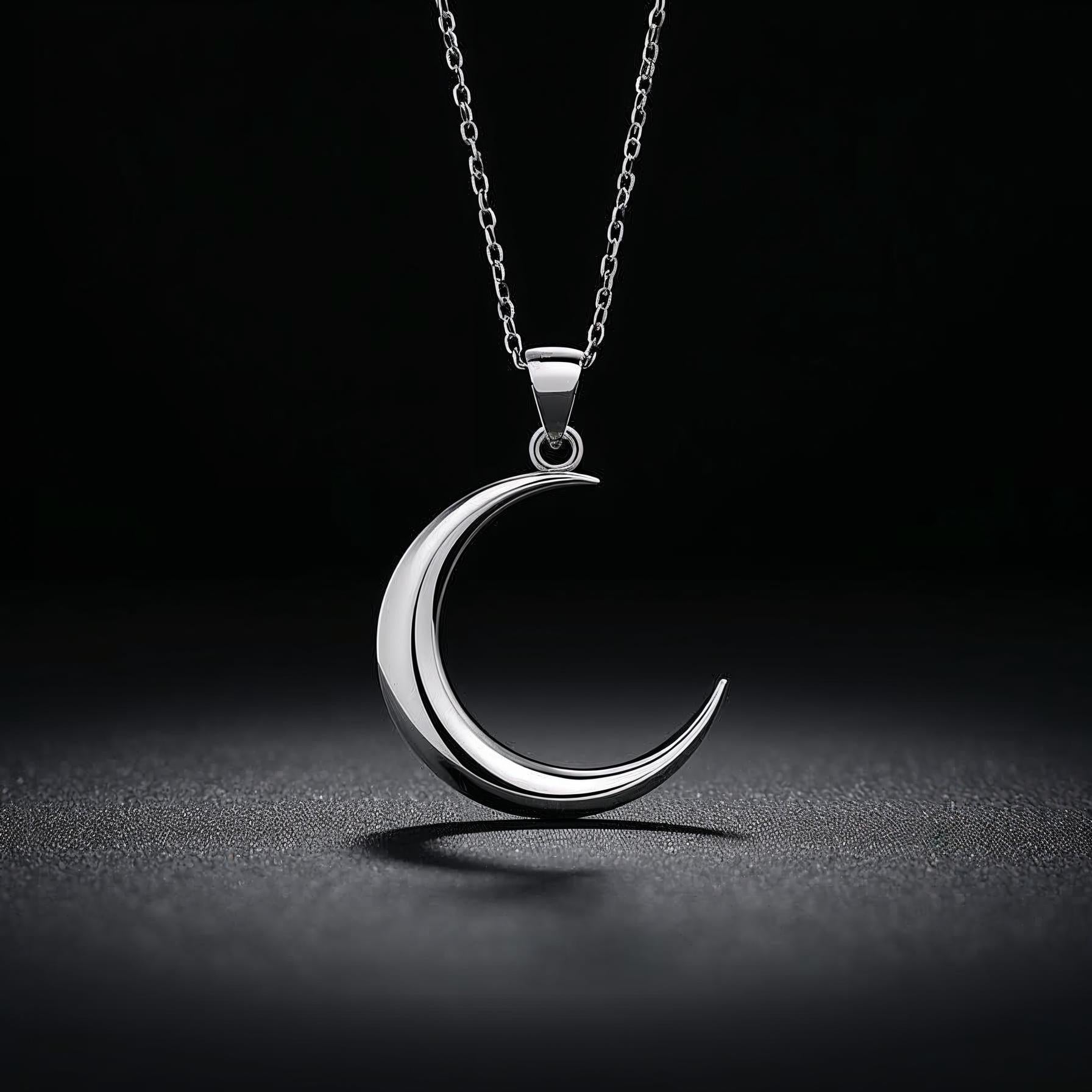 Silver crescent moon pendant on a dark background