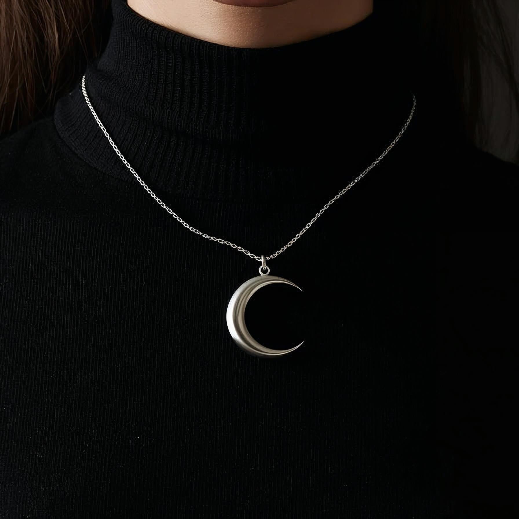Silver crescent moon necklace on a black turtleneck