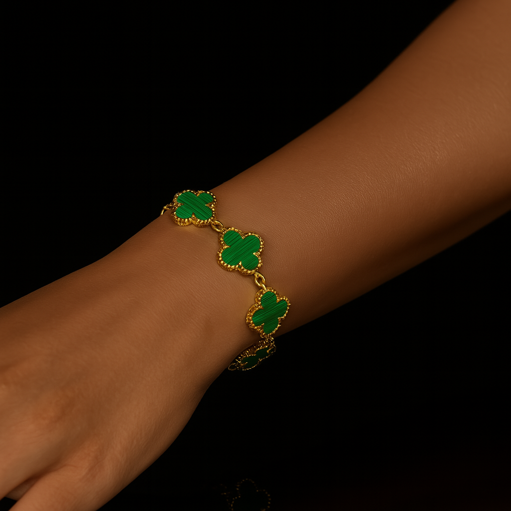 Gold bracelet with green clover-shaped stones on a black background