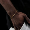 Gold bracelet on a wrist against a dark background