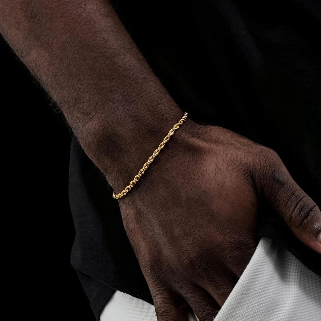 Gold bracelet on a wrist against a dark background