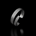Silver ring with intricate design on a black background