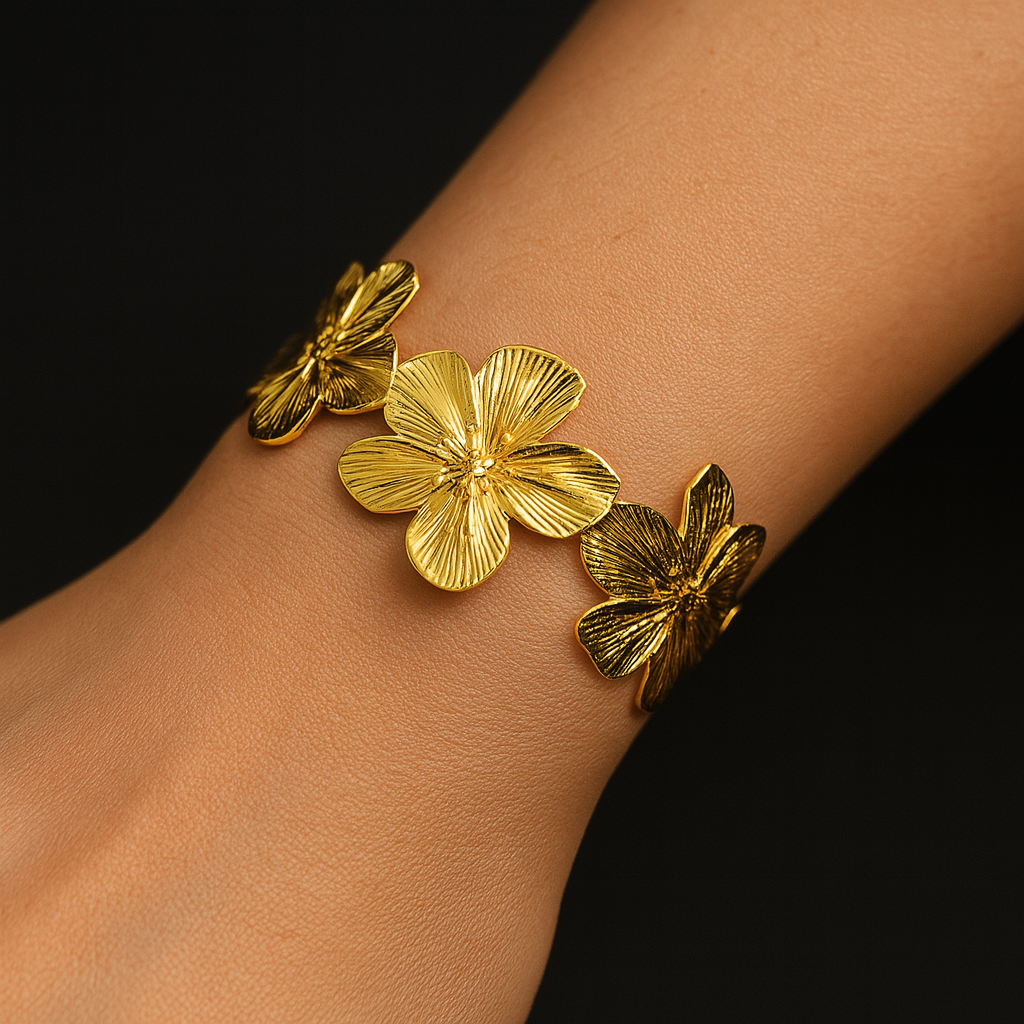 Gold bracelet with floral and butterfly designs on a wrist against a black background