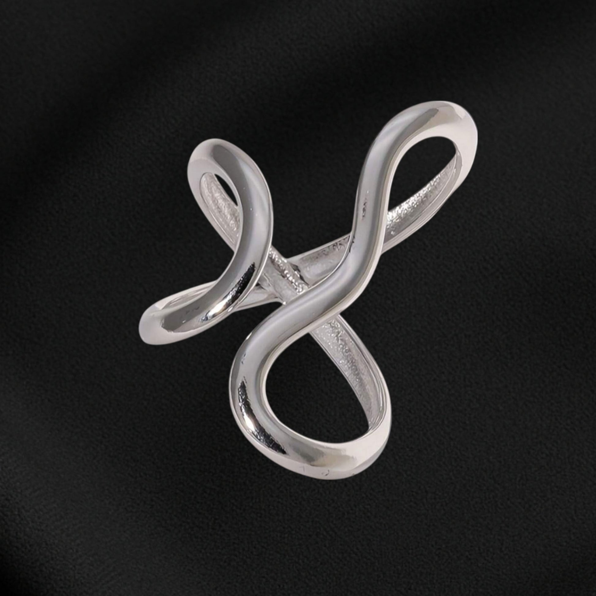 Silver infinity symbol brooch on black fabric