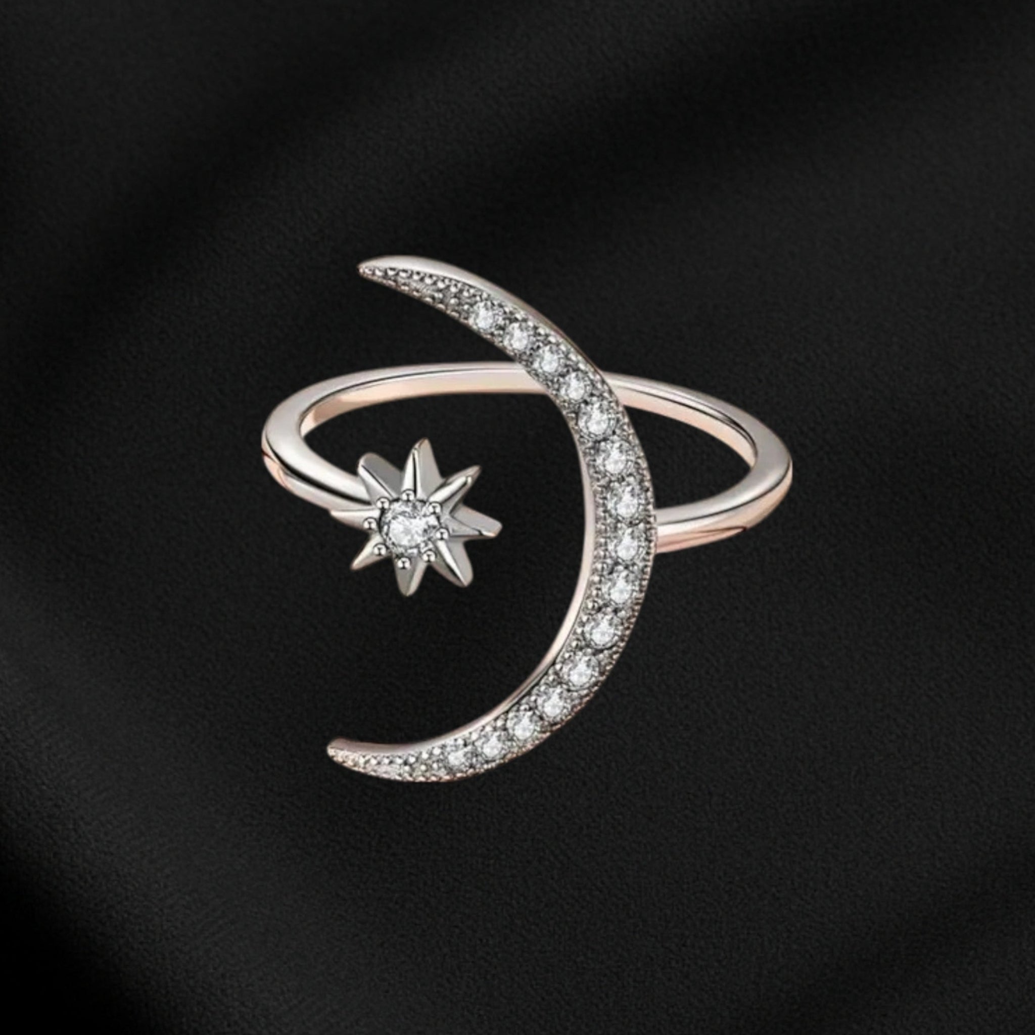 Silver ring with moon and star design on a black background