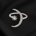 Silver ring with moon and star design on a black background