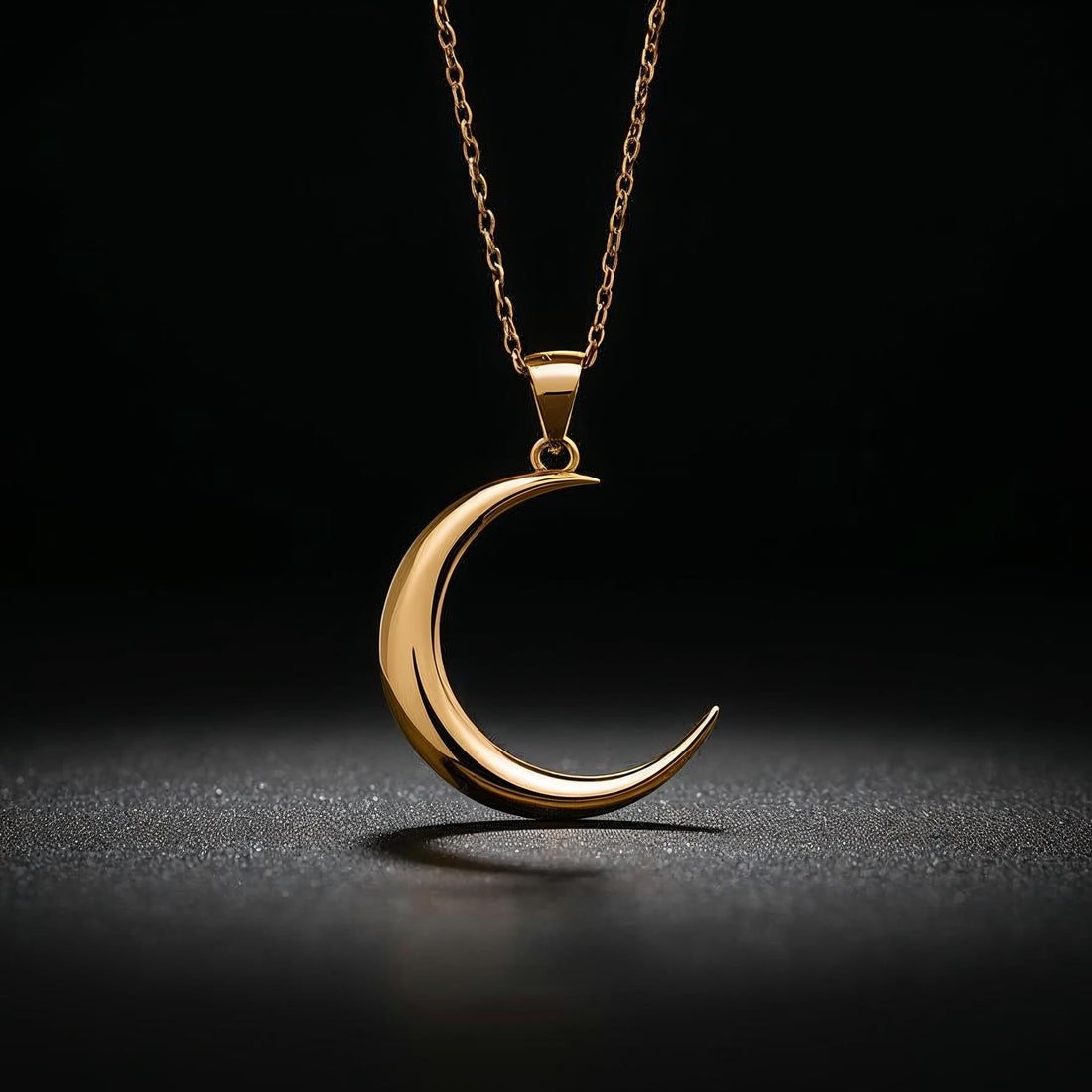 Gold crescent moon necklace on a black background