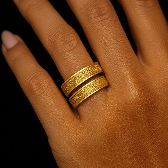 Hand wearing two gold rings with a dark background