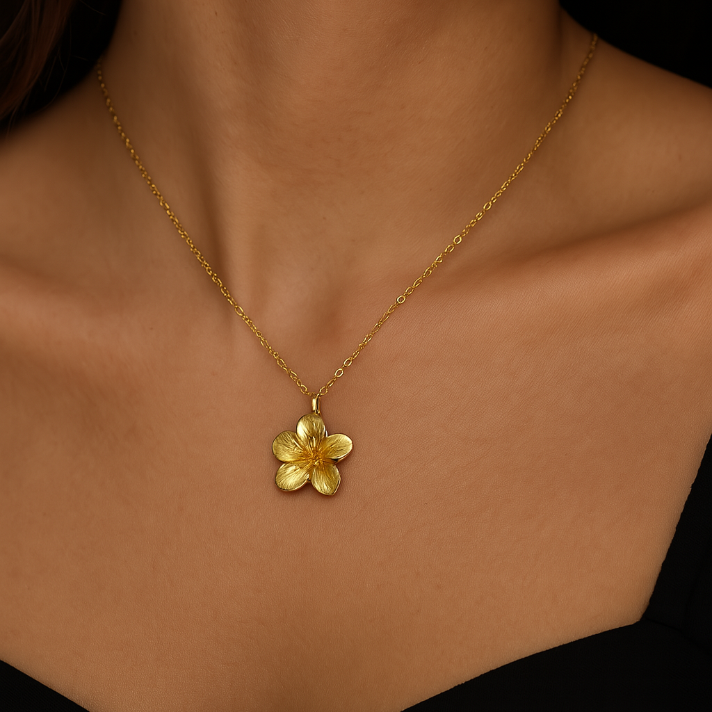 Gold necklace with a floral pendant on a person's neck against a black background