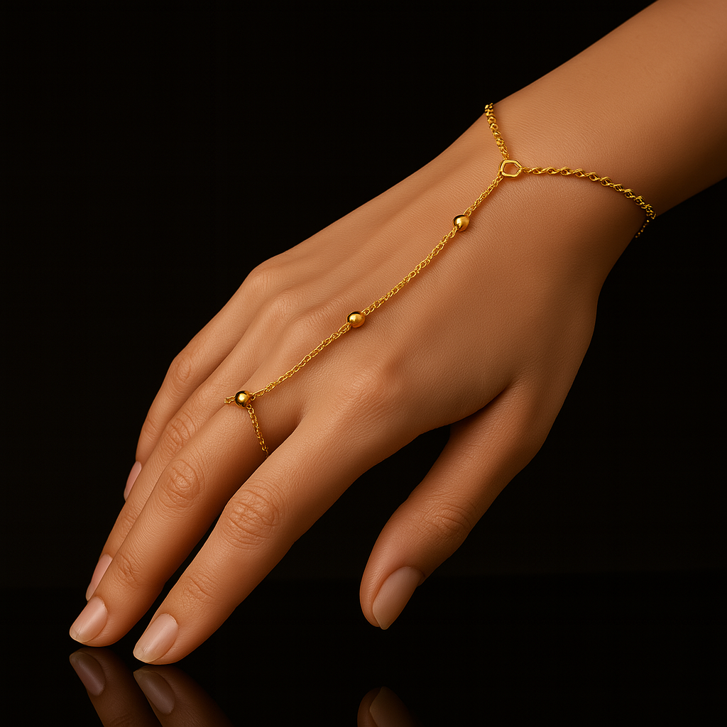 Gold hand chain on a hand against a black background