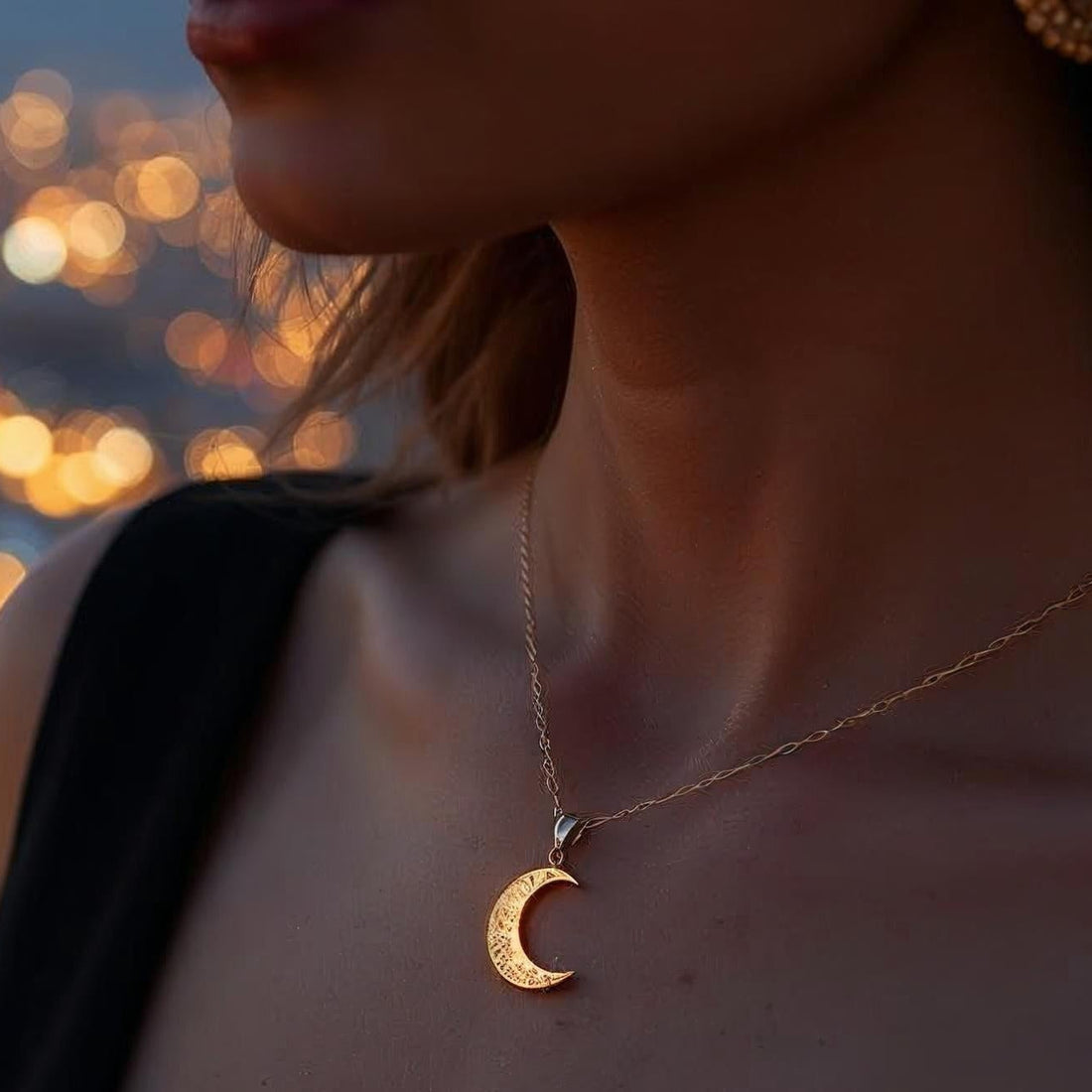 Gold crescent moon pendant on a chain against a black background