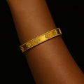 Gold bracelet on a person's wrist against a black background