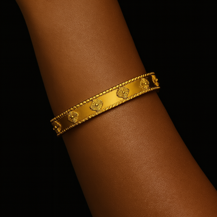 Gold bracelet on a person's wrist against a black background